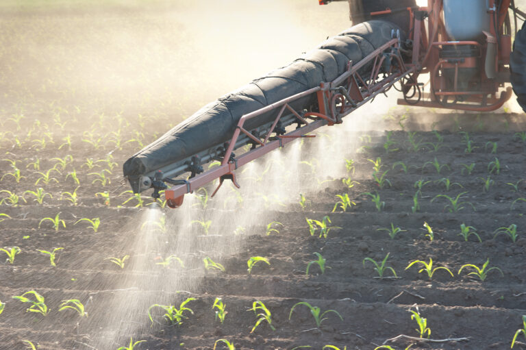 Tractor spraying a mist of fertilizer on an open crop field